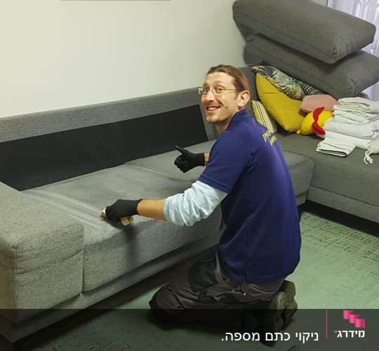 אדם מנקה ספה עם מברשת וכפפות שחורות